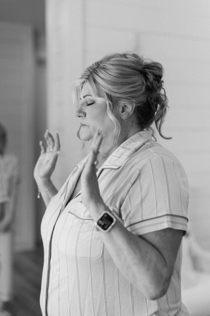 Black and white close up of brides mother praying over everyone at The Farmhouse wedding