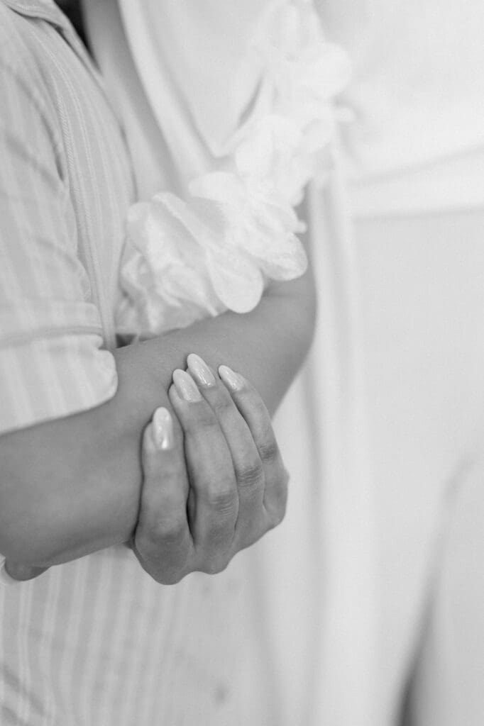 Black and white close up of bride and junior bridesmaid holding hands during prayer in the bridal suite at The Farmhouse
