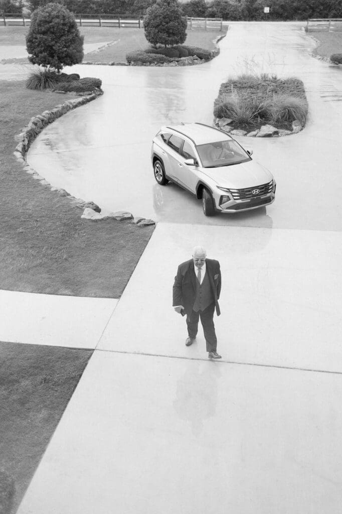 Black and white photo of the brides father walking into the venue at The Farmhouse