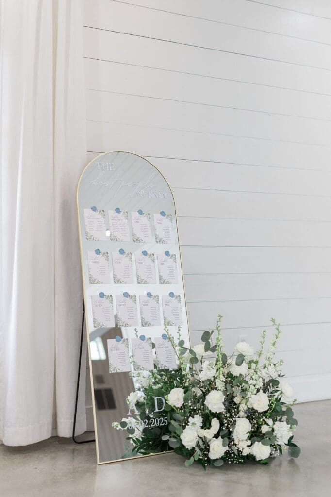 Gold arched mirror with table numbers and names for guests at The Farmhouse wedding