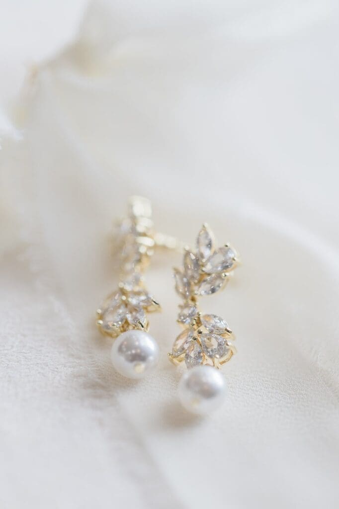 Flatlay detail of dangling earrings with gold, diamonds, and pearls.