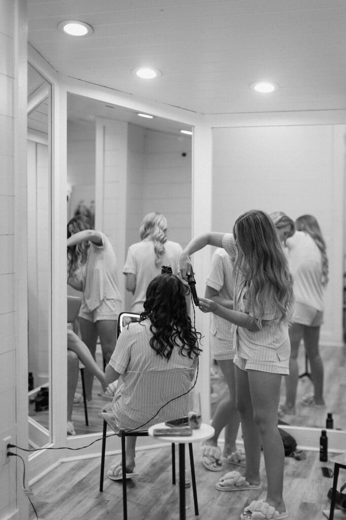 Black and white portrait of bridesmaids doing hair and make up in the bridal suite at The Farmhouse