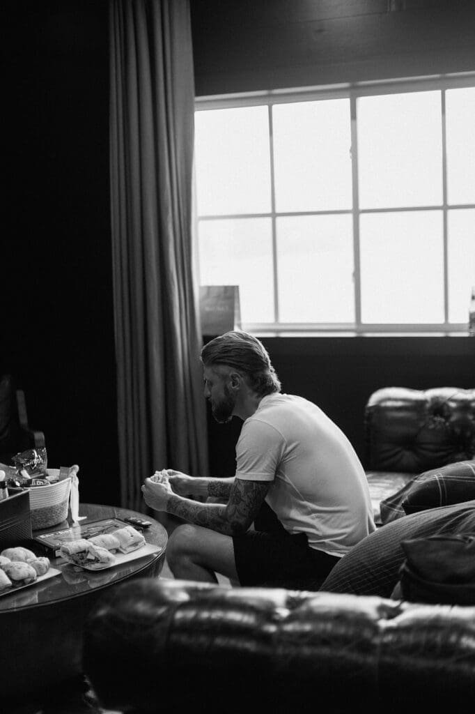 Black and white image in the grooms suite of the groomsmen preparing for the wedding day at The Farmhouse