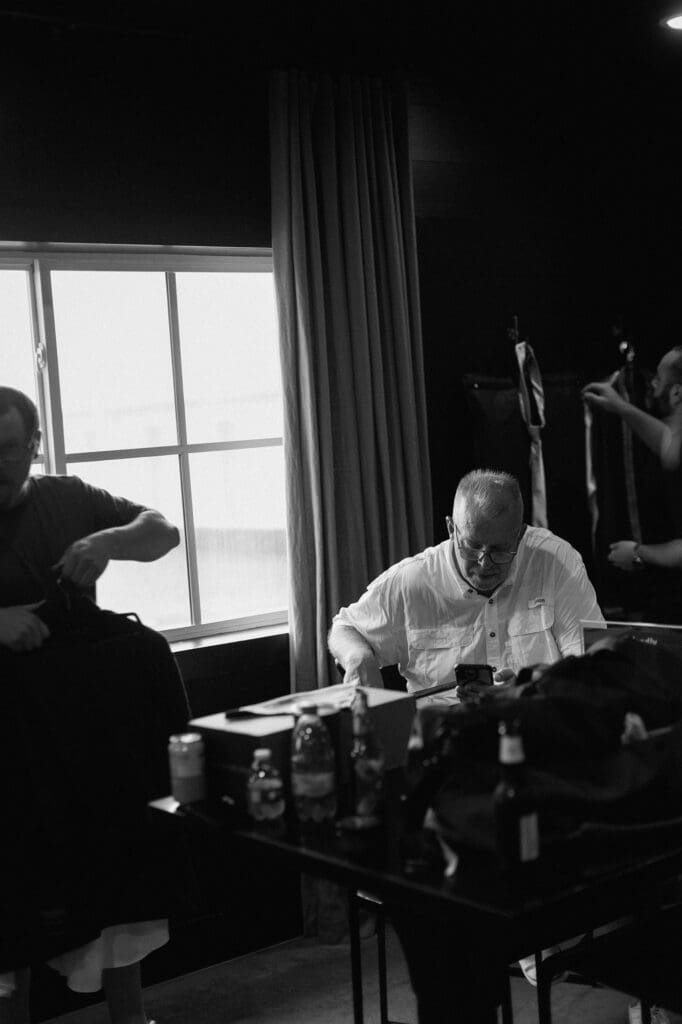 Black and white image in the grooms suite of the groomsmen preparing for the wedding day at The Farmhouse