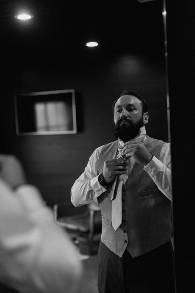 Black and white image in the grooms suite of the groomsmen preparing for the wedding day at The Farmhouse