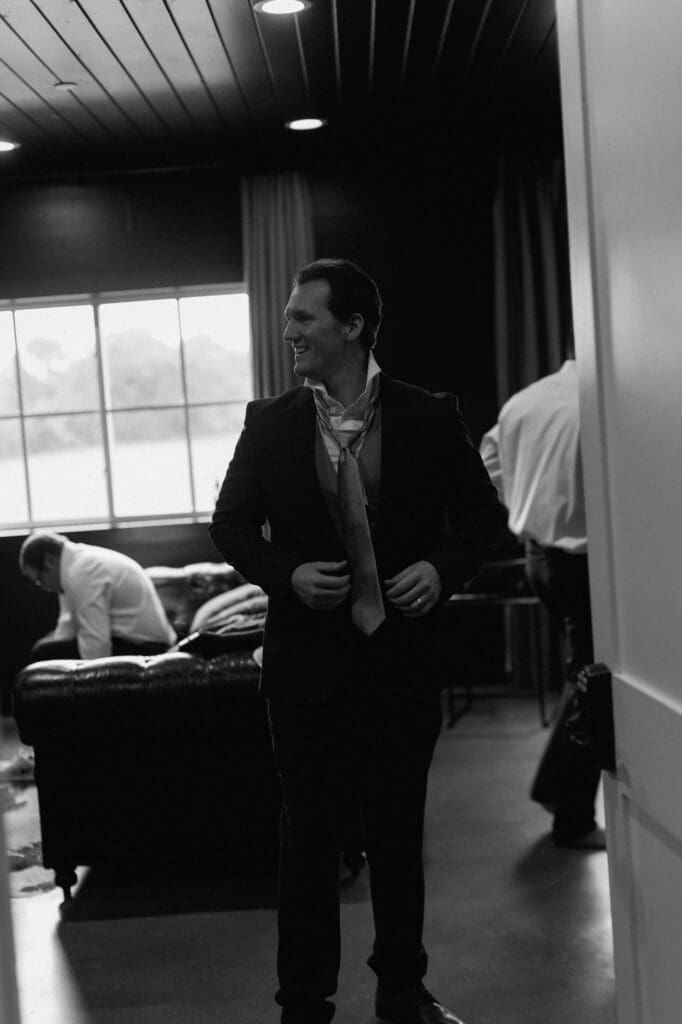 Black and white image in the grooms suite of the groomsmen preparing for the wedding day at The Farmhouse