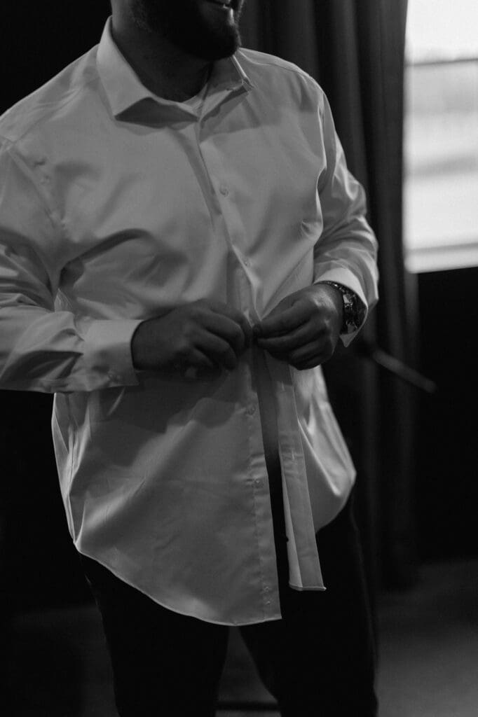 Black and white image in the grooms suite of the groomsmen preparing for the wedding day at The Farmhouse