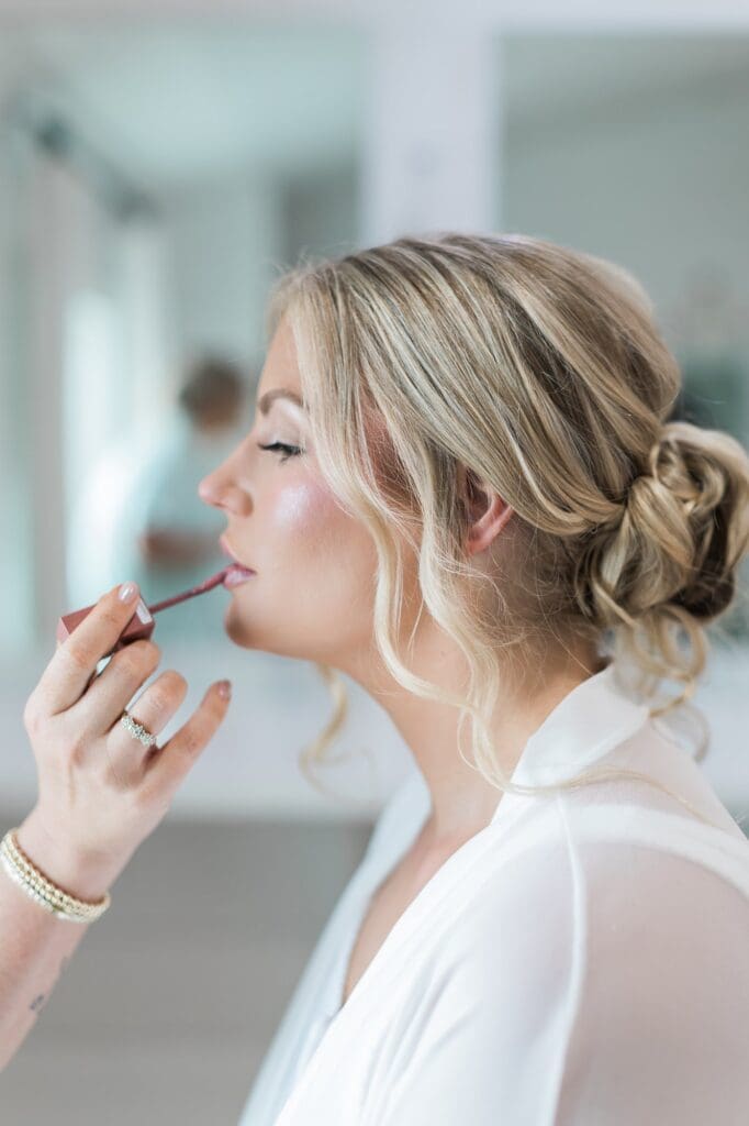 Bride getting the final touch ups for her bridal make up on her wedding day at The Farmhouse.