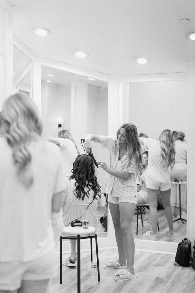 Black and white bridesmaids curling hair and getting ready for the wedding day at The Farmhouse