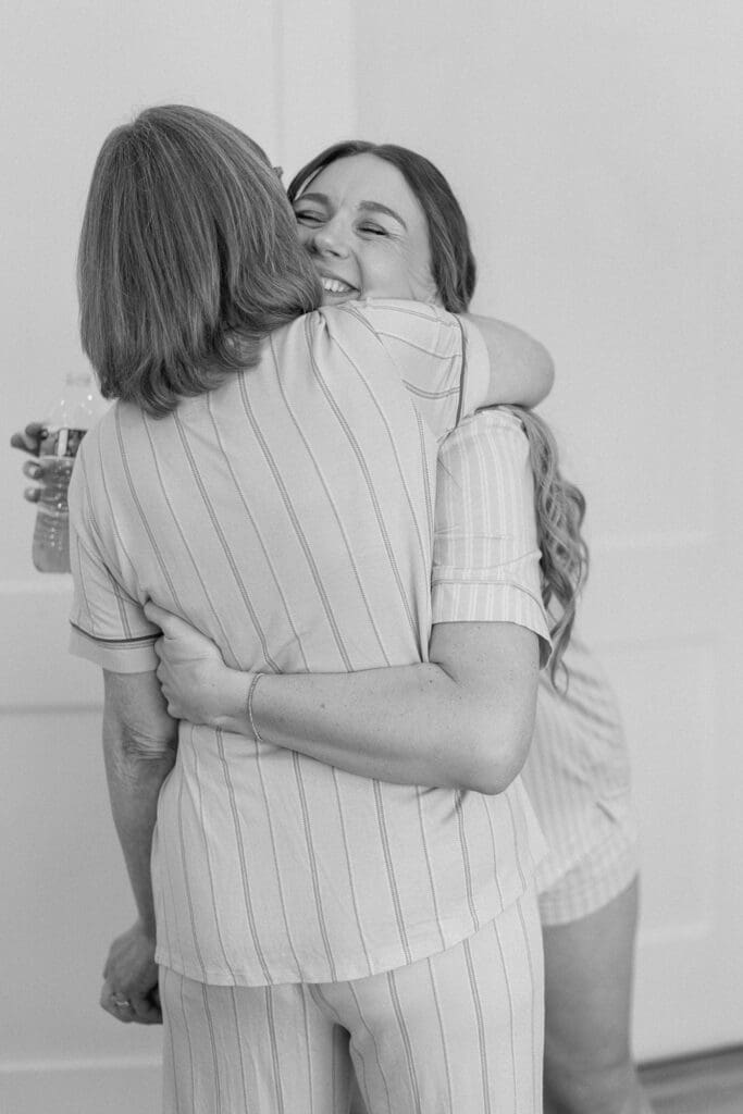 Bridesmaids hugging mother in law in black and white in the bridal suite at The Farmhouse
