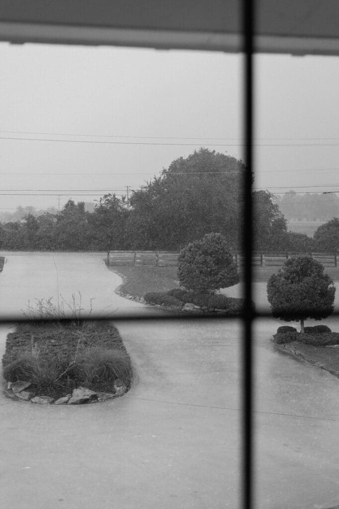Black and white portrait outside the window of a rainy wedding day at The Farmhouse