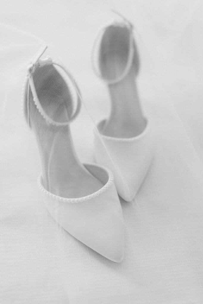 Black and white flatlay of bridal shoes with the veil over it
