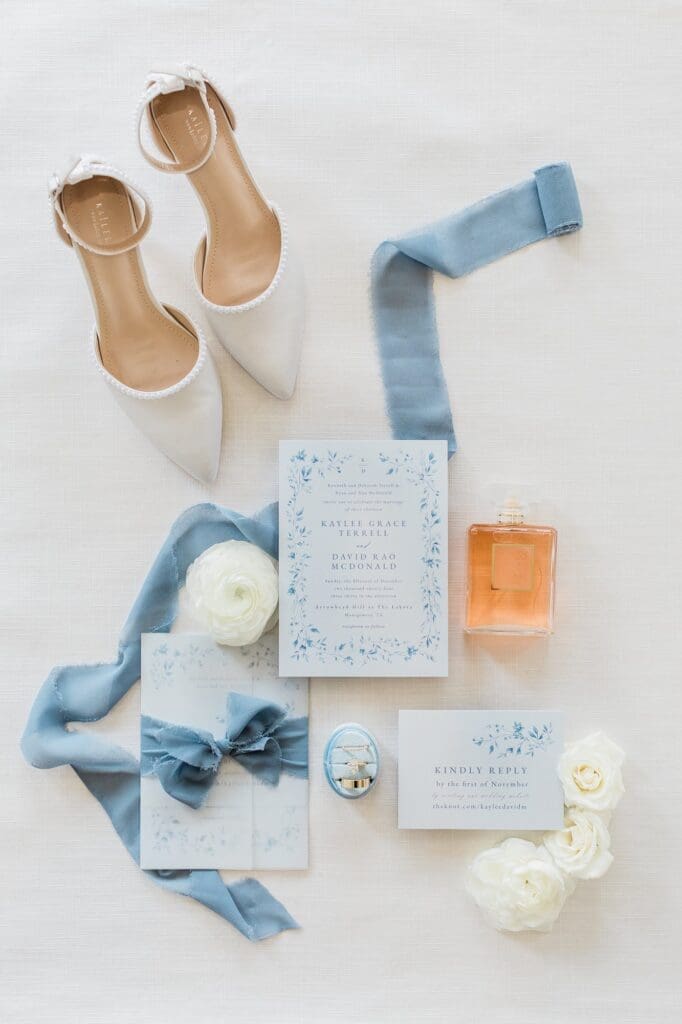 Dusty blue winter wedding flatlay of invitation suite and wedding details