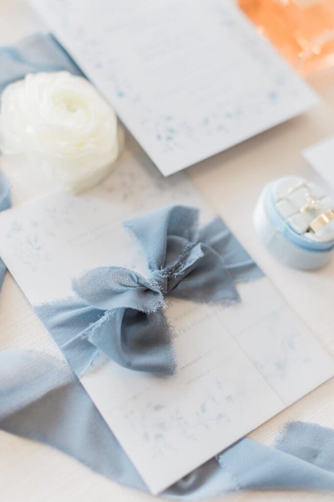 Dusty blur ribbon tied around wedding invitation suite