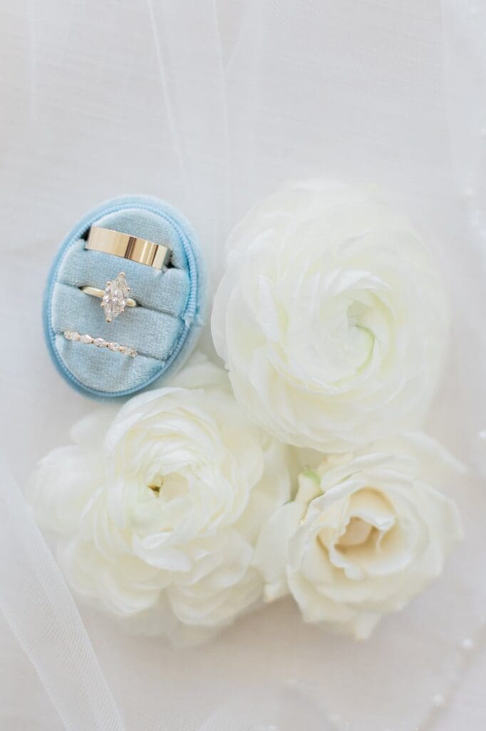 3 wedding rings in a dusty blue velvet ring box next to white flowers