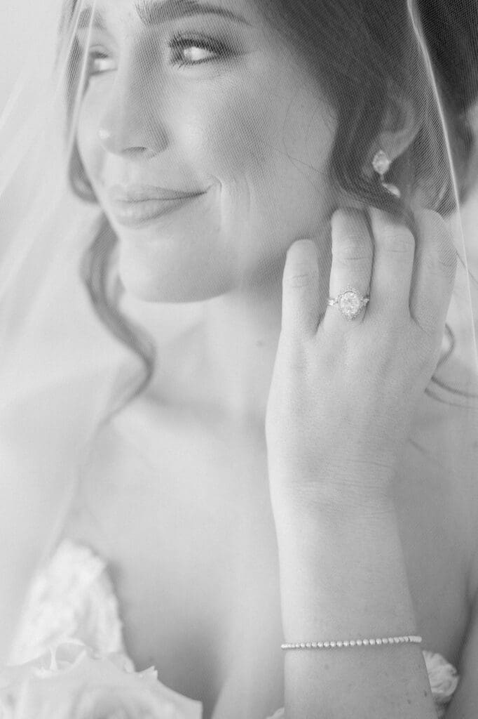 Up close black and white shot of the bride looking away from the camera, smiling, and showing off her wedding ring