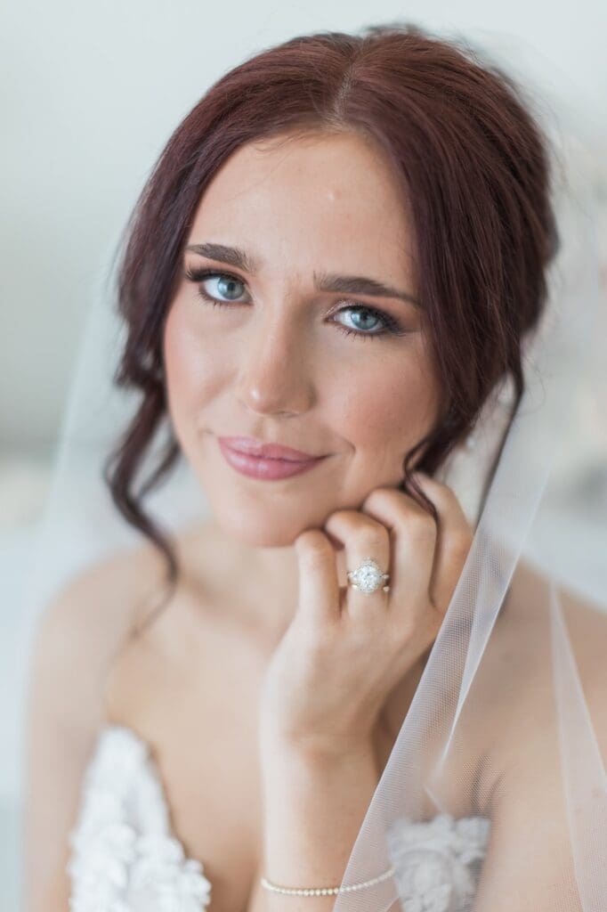 Beauty shot of bride looking at the camera with a slight smile and her hand on her face