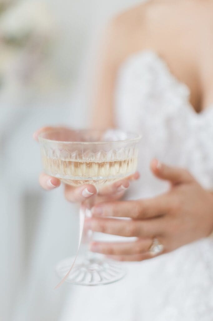 Close up of bride holding a crystal champagne glass with champagne in it 
