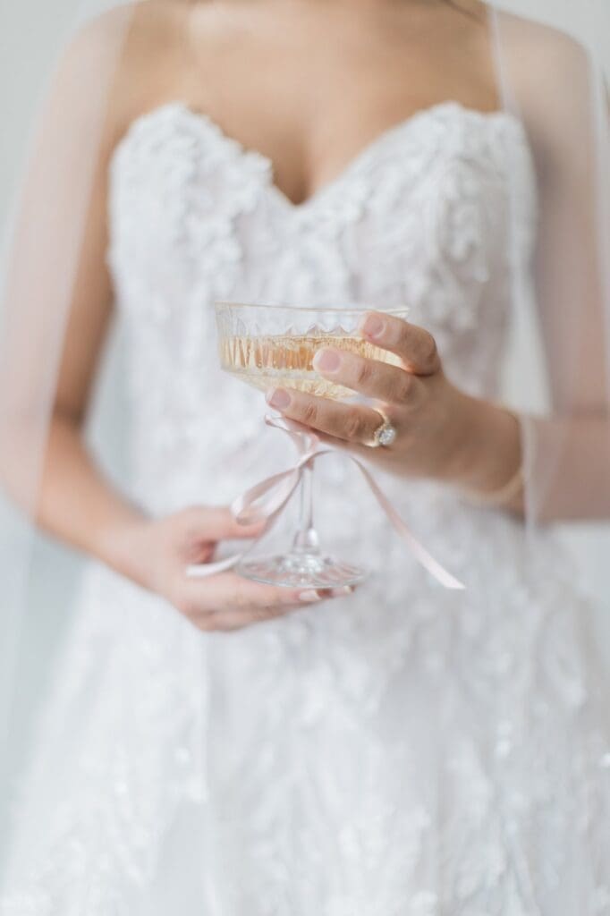 Close up of bride holding a crystal champagne glass with champagne in it 