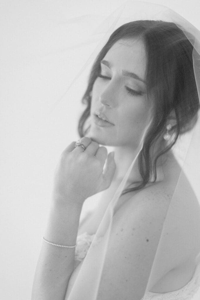 Black and white portrait under her veil with eyes cast downwards and hand under her chin.