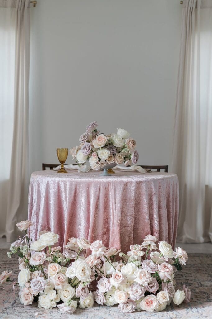 Sweetheart wedding table surrounded by neutral white, blush, and soft lavender roses with a textured blush tablecloth.
