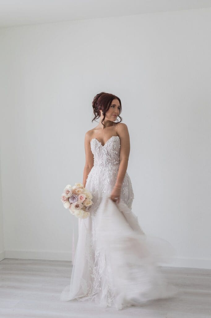 Bride swishing her dress around. She is in focus, but her dress is slightly burred due to movement.