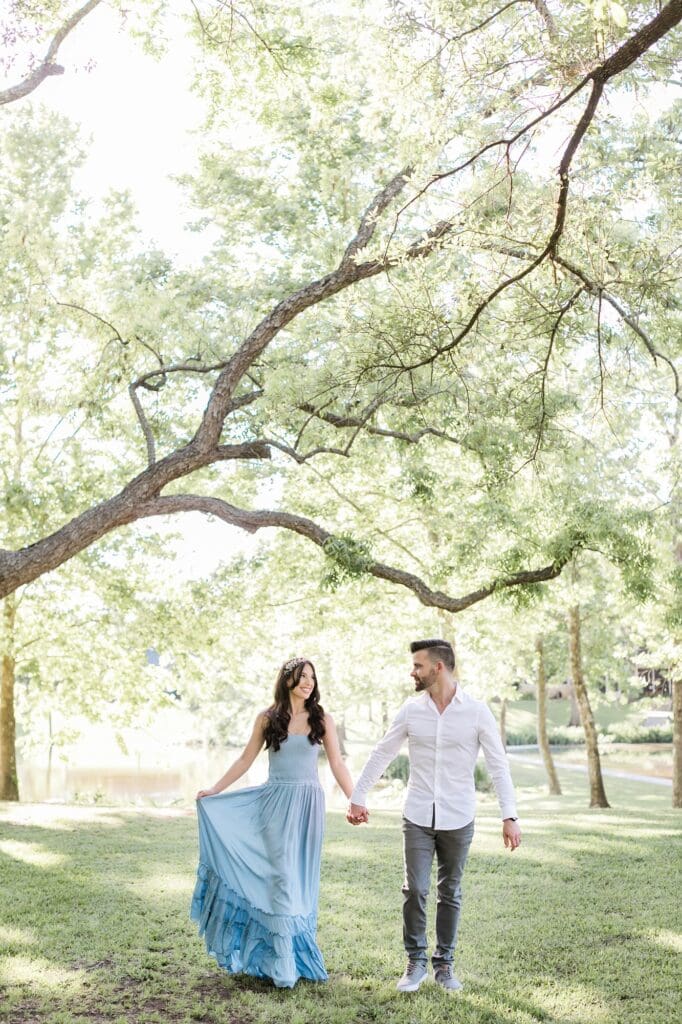 Couple walking hand and hand under the pecan trees for their orchard at caney creek engagement session