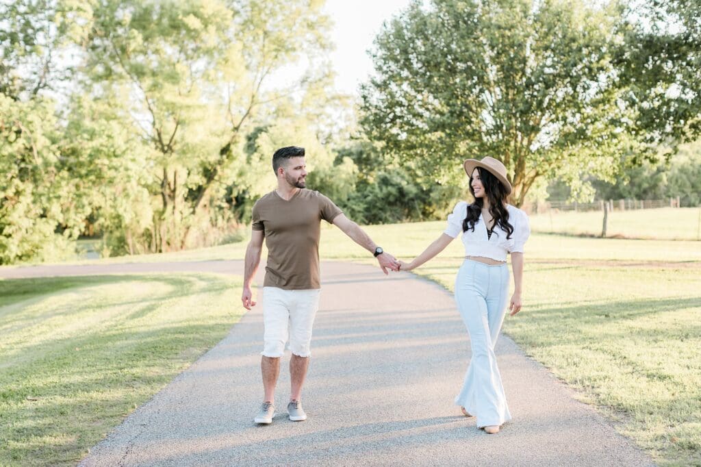 bride and groom walking holdings hands during their engagement session at the orchard at caney creek