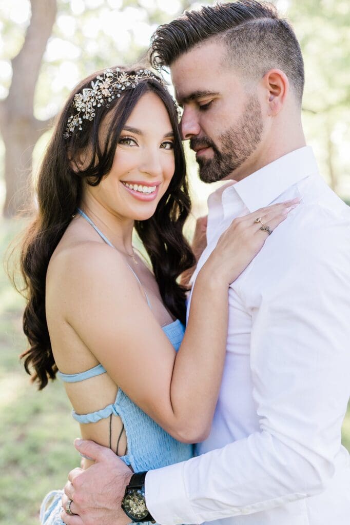 Couple snuggling into each other for their engagement session at the orchard at caney creek
