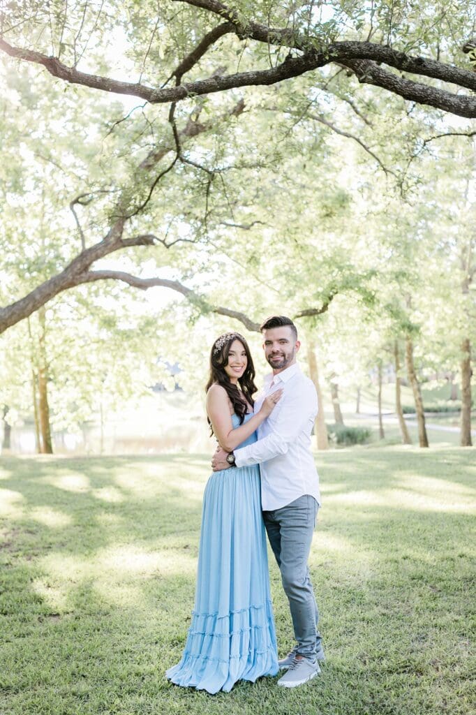Bride and groom smiling for the camera under the pecan trees at the orchard at caney creek for their engagement session