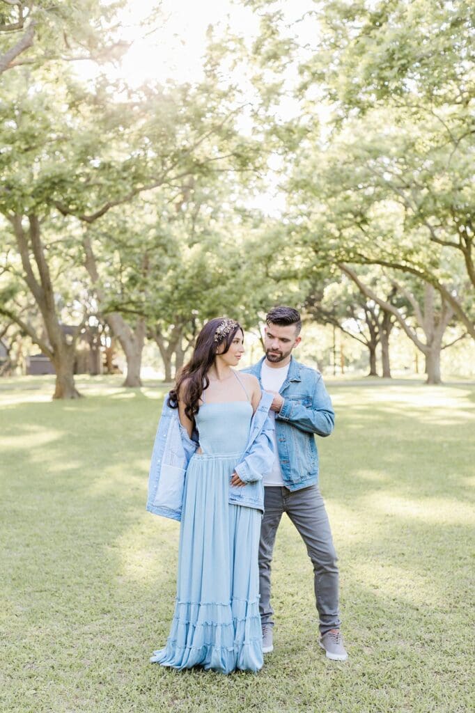 Groom helping bride put her jacket on for their engagement session at the orchard at caney creek