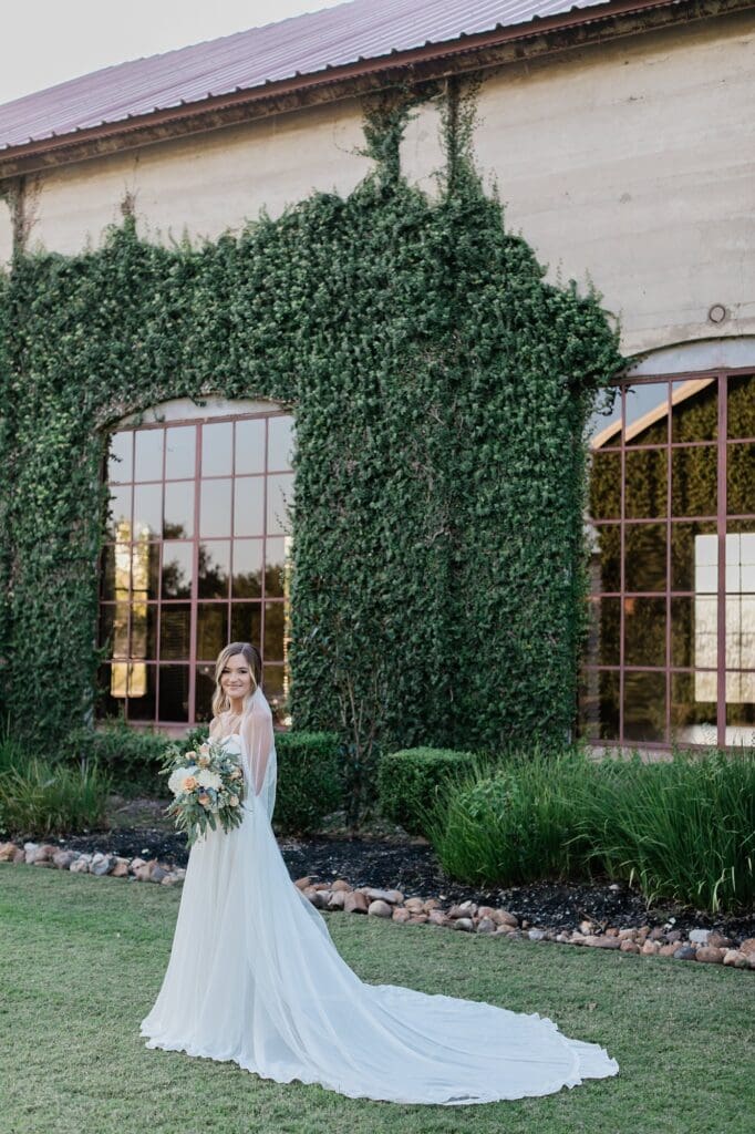 Bride standing in front of the chapel for her bridals at Olde Dobbin Station. There is beautiful green vines crawling up the wall.
