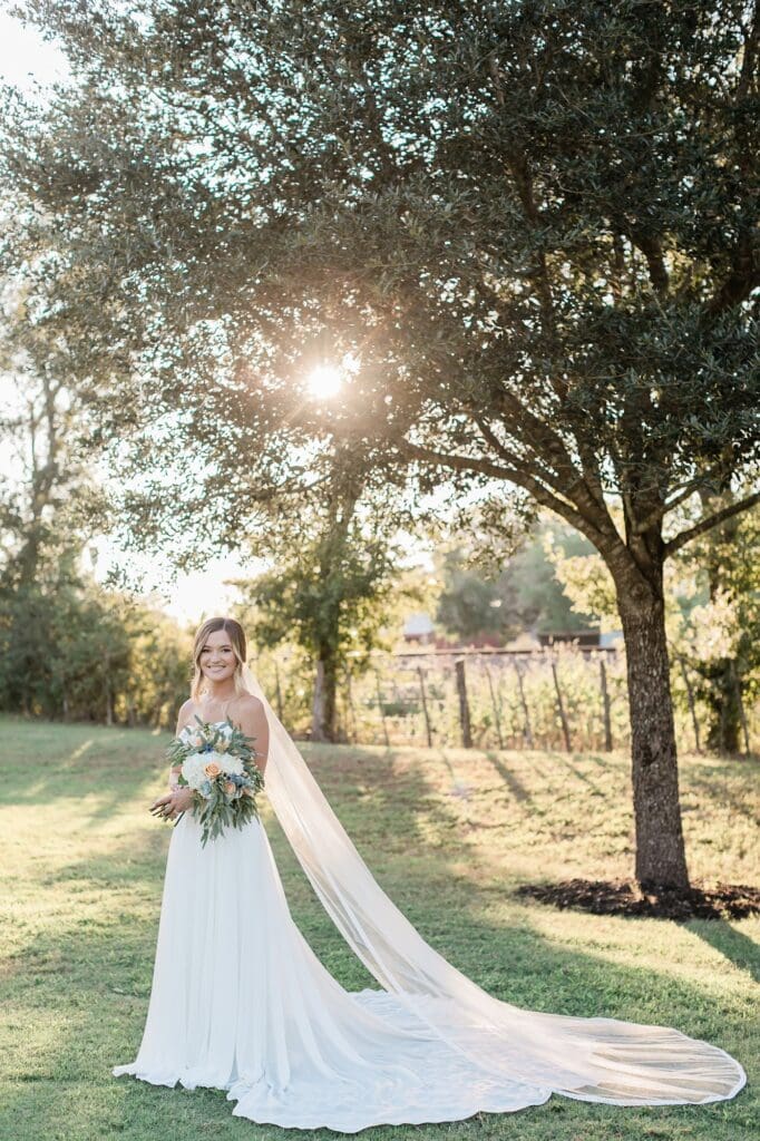 Bride smiling at the camera and posing outside in front of the train tracks at Olde Dobbin Station