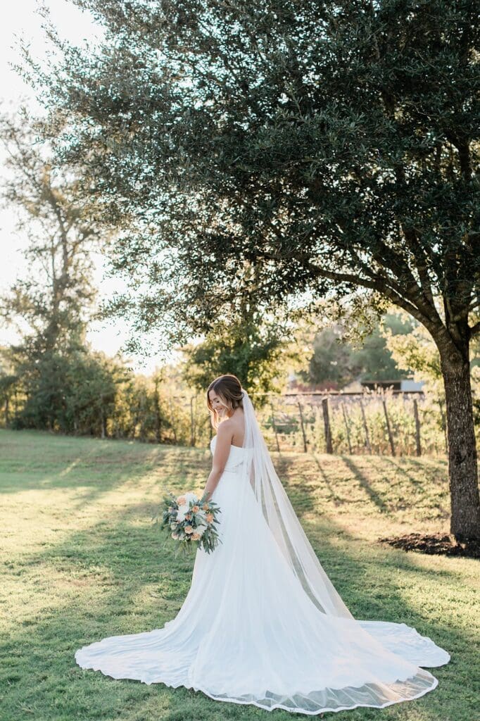 Bride standing near the train tracks at Olde Dobbin Station smiling down at the ground