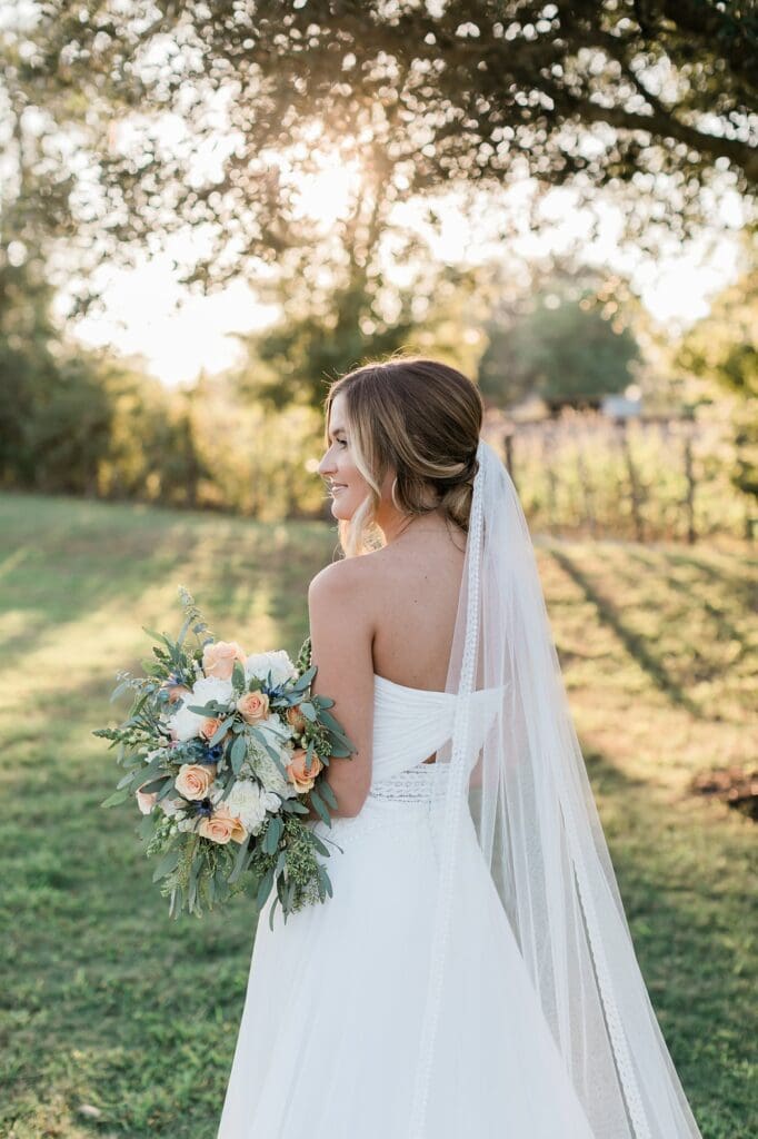 Bride holding her bouquet and smiling out in the distance for her bridal portraits at Olde Dobbin Station