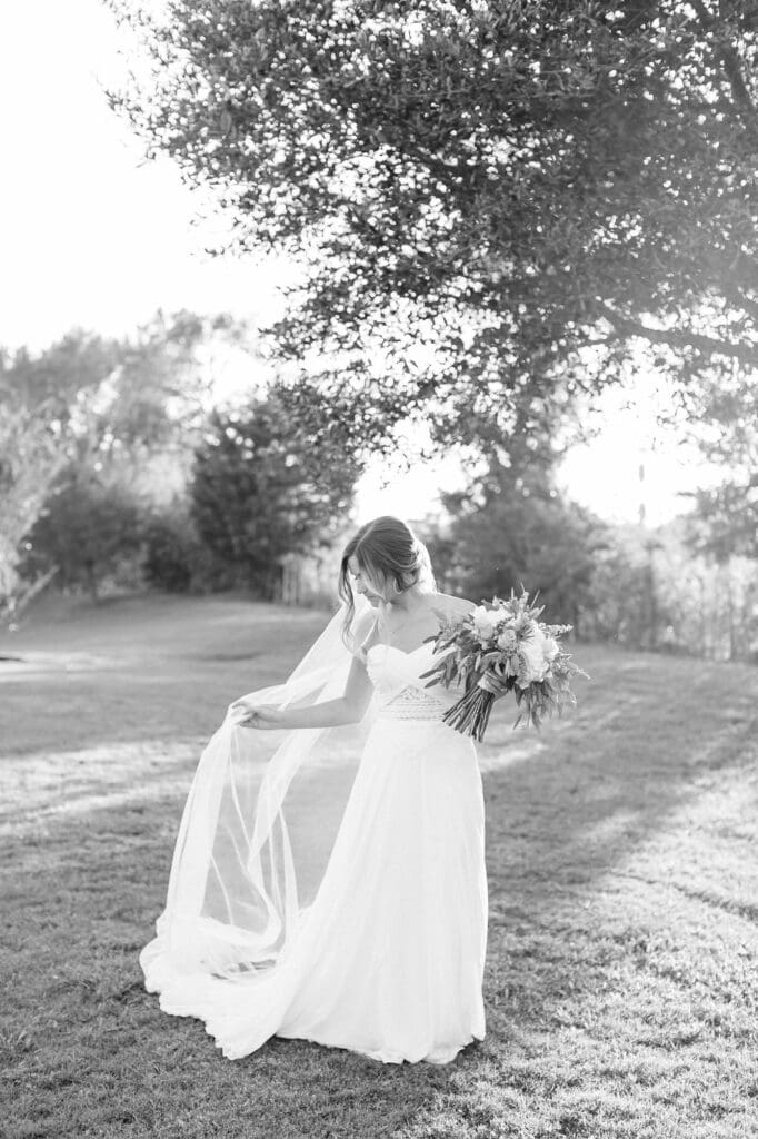 Black and white emotive photo of bride fixing her veil during her bridal portraits at Olde Dobbin Station