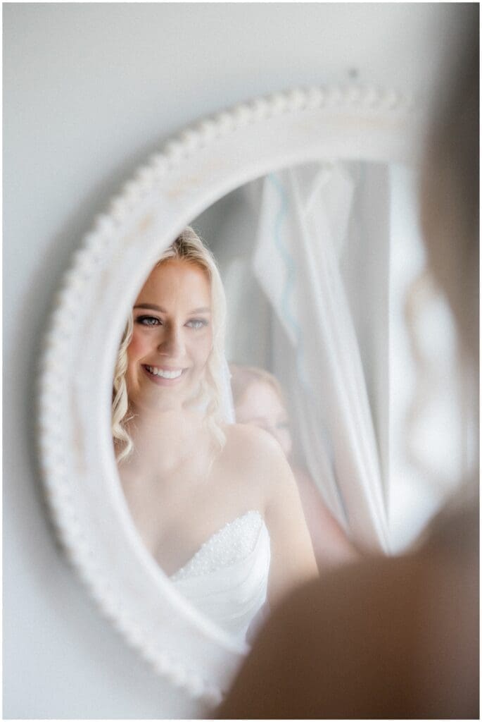 Bride smiling in the mirror, holding back tears, at Addison Woods