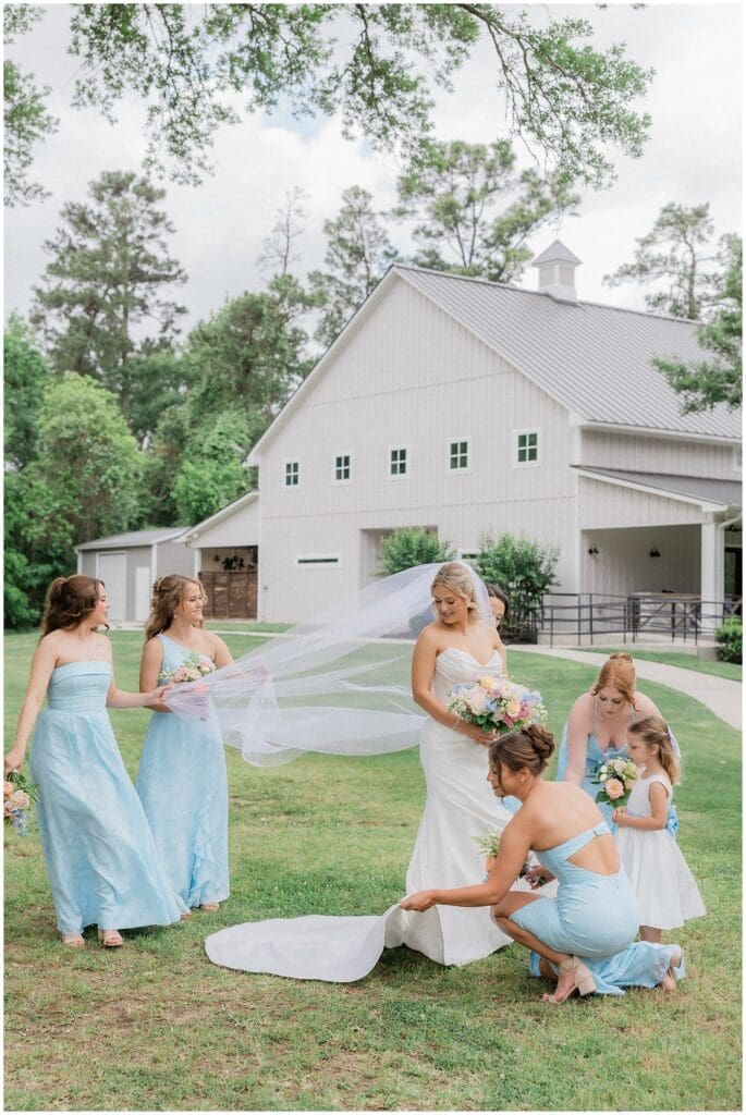 Bridesmaids fluffing dress and veil outdoors at Addison Woods