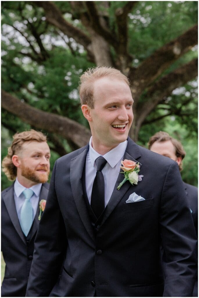 Groom smiling with groomsmen during groomsmen portraits at Addison Woods