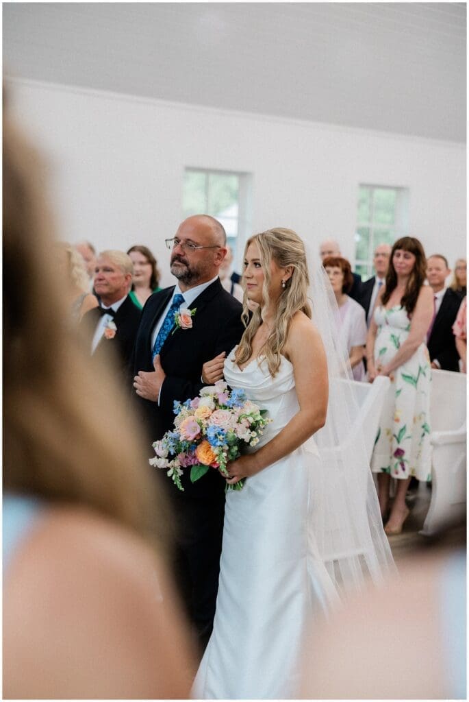 Father giving away bride during ceremony at Addison Woods