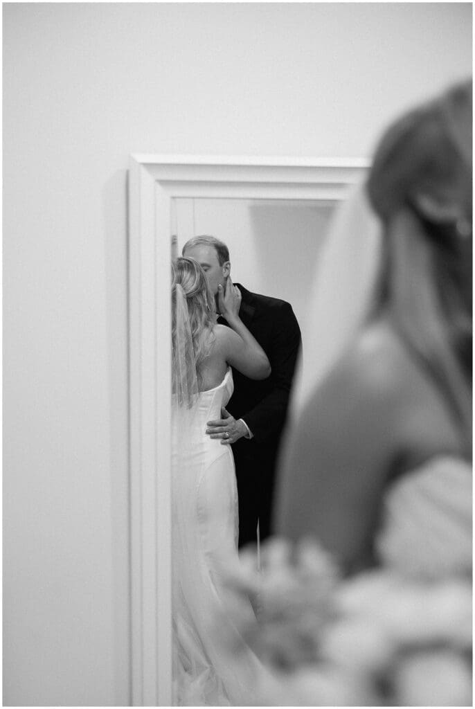 A private moment of the groom kissing the bride, taken in the reflection of the mirror at Addison Woods