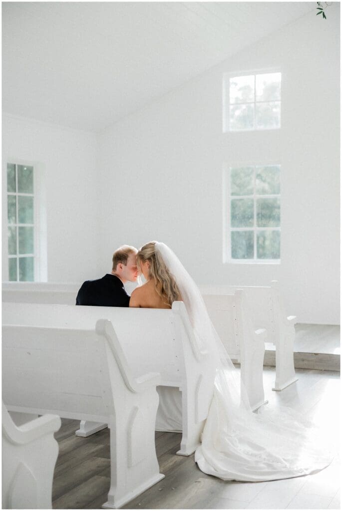 Bride and groom sitting in the chapel pews together at Addison Woods