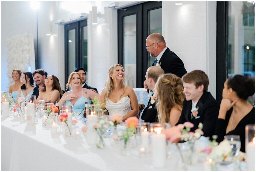 Bride smiling at father during toasts at Addison Woods