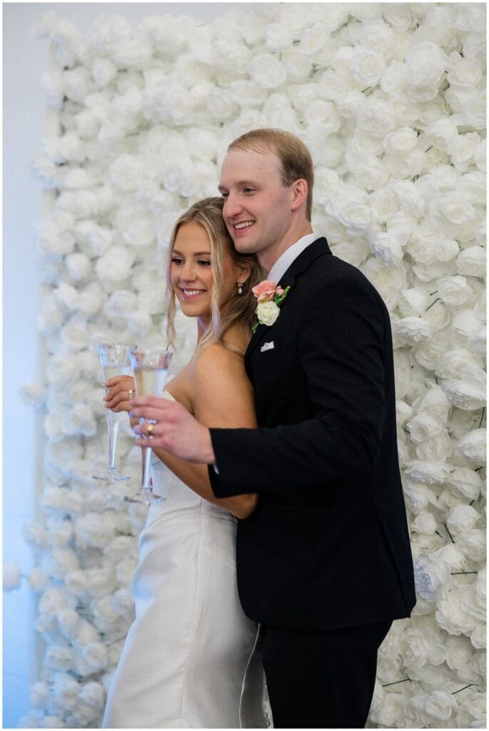 Bride and groom standing in front of a flower wall at Addison Woods