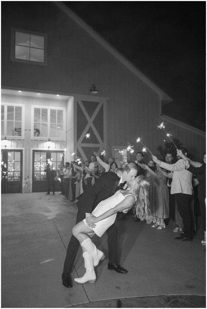 Groom dipping and kissing the bride under sparklers at Addison Woods