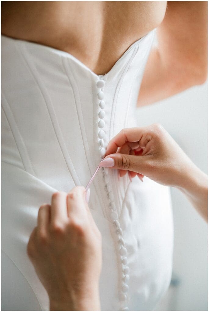 Bridesmaids helping bride button her dress at Addison Woods