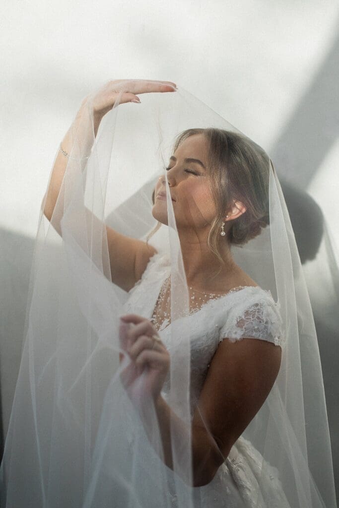 Bride playing under her veil in the light at Iron Manor