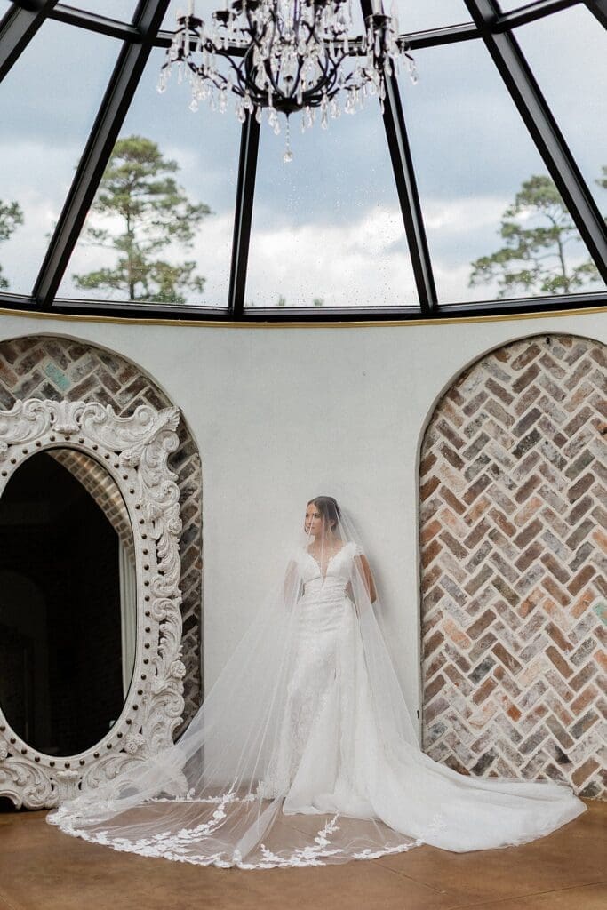 Bride posing with her long veil draped over her in the bridal suite at Iron Manor