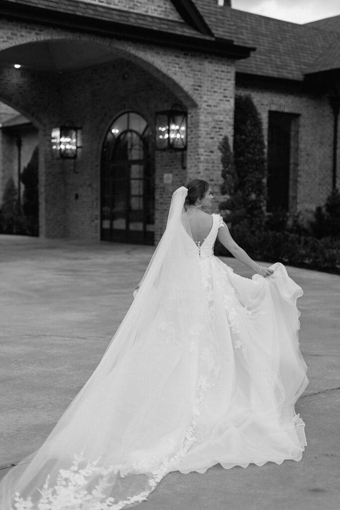 Black and white portrait of bride running away from the camera with her dress flowing at Iron Manor
