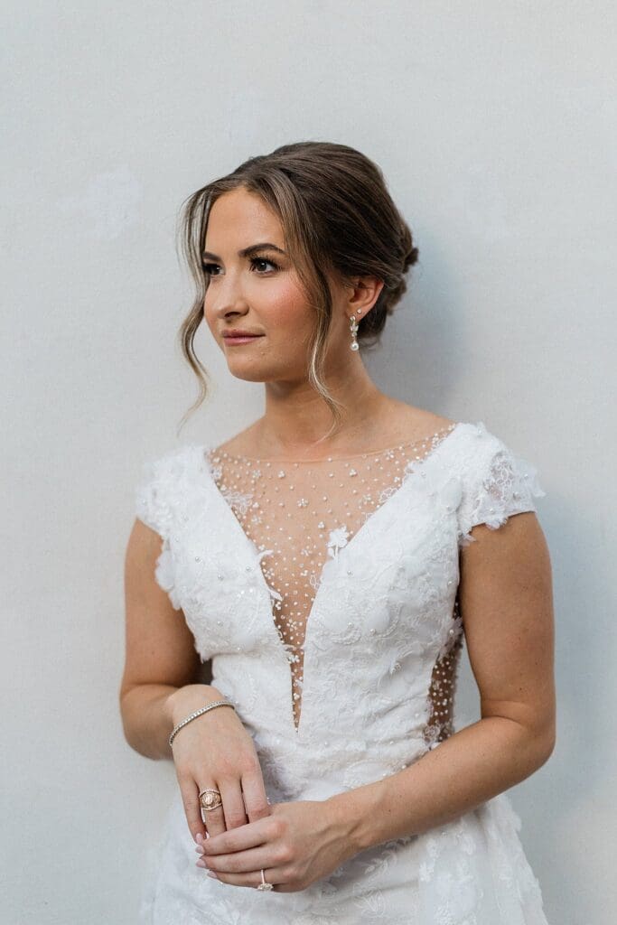 Bride standing next to a white wall posing for bridal portraits at Iron Manor